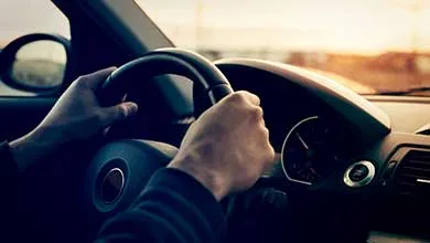 Driving a car in sunny day - focus on steering weel