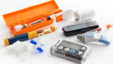 Diabetes management tools: insulin pump, pen, blood glucose meter, syringe, and sugar cubes on white.