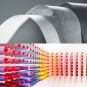 Composite image with two sections: the top shows curved layers of textured gray woven fabric; the bottom displays rows of colorful thread spools arranged in a gradient from purple and blue to yellow, orange, and red, with the spools decreasing in size toward the right.